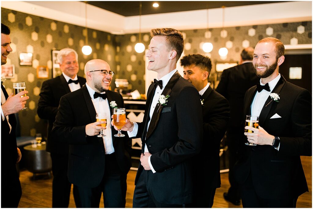 A groom shares drinks with groomsmen in a suite at Perona Farms.