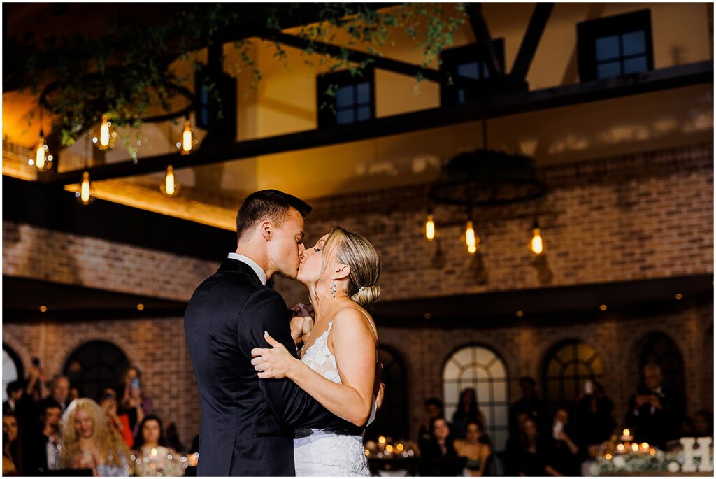 A bride and groom kiss on the dance floor.