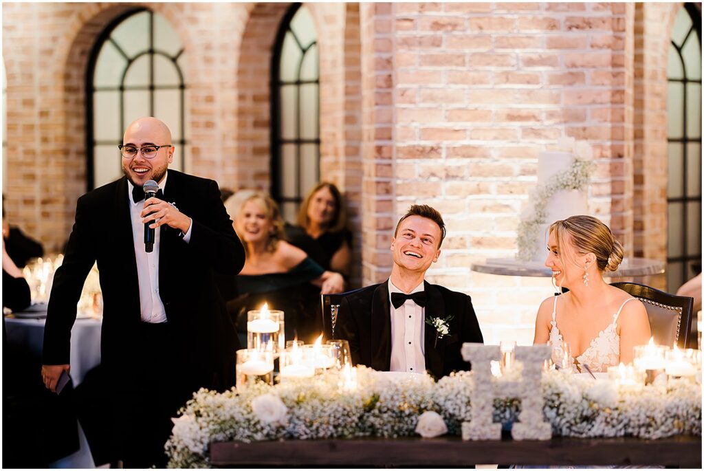 A groom laughs during a best man's speech.