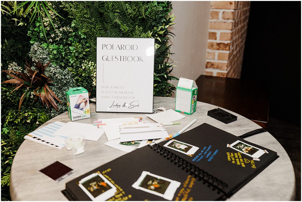 A Polaroid guestbook sits on a table at a wedding reception.