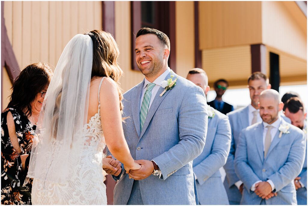 A groom laughs during a wedding ceremony.