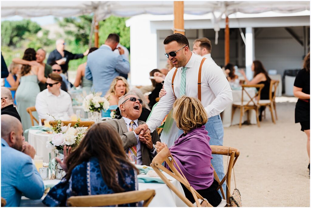 A groom greets guests during a wedding cocktail hour.