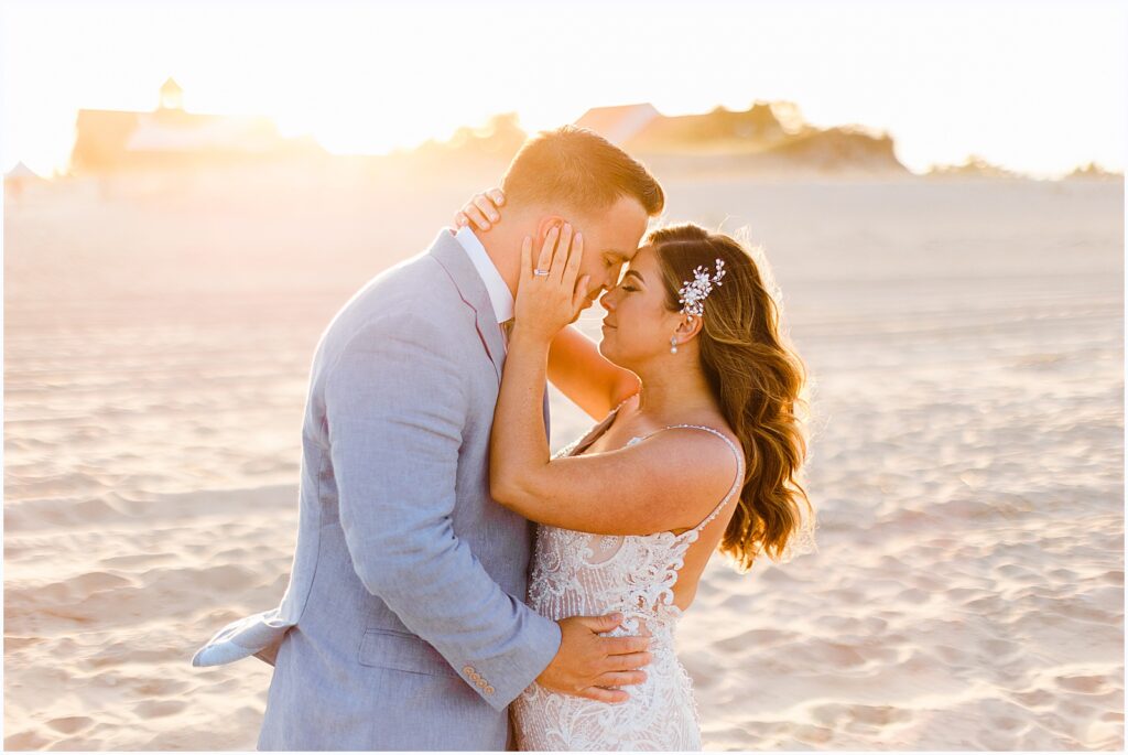The sun sets behind a bride and groom on the beach in Delaware.