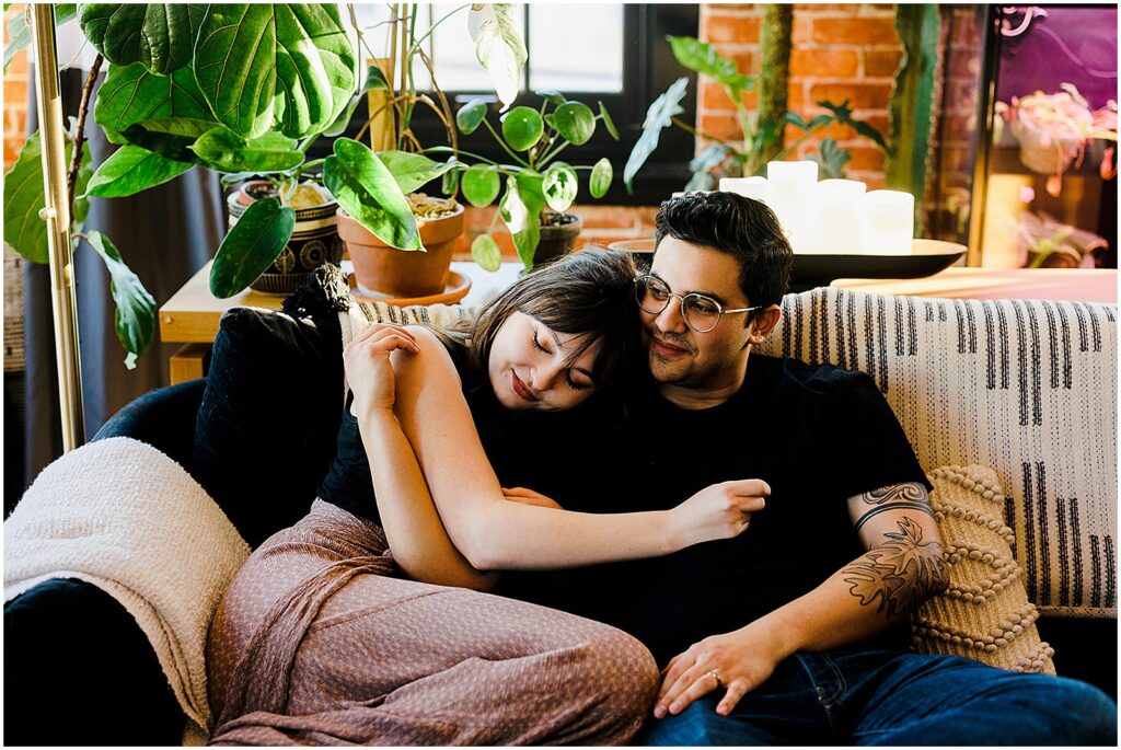 A husband and wife cuddle on a couch for anniversary photos.
