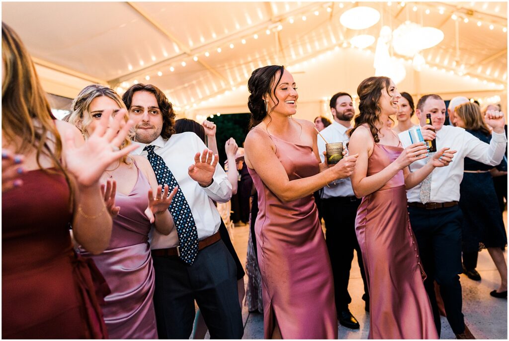 A line of bridesmaids in pink dresses dance.