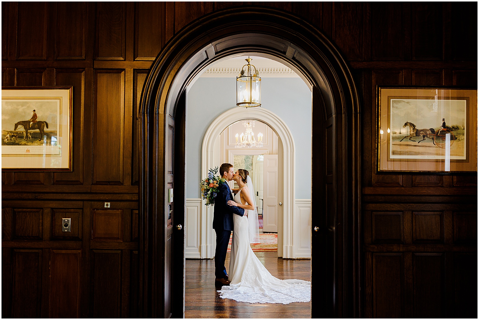 A bride and groom kiss in the hall at Bellevue Hall.