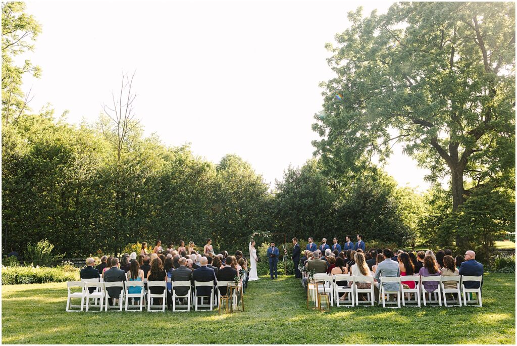 An outdoor wedding ceremony takes place in the gardens at Bellevue Hall.