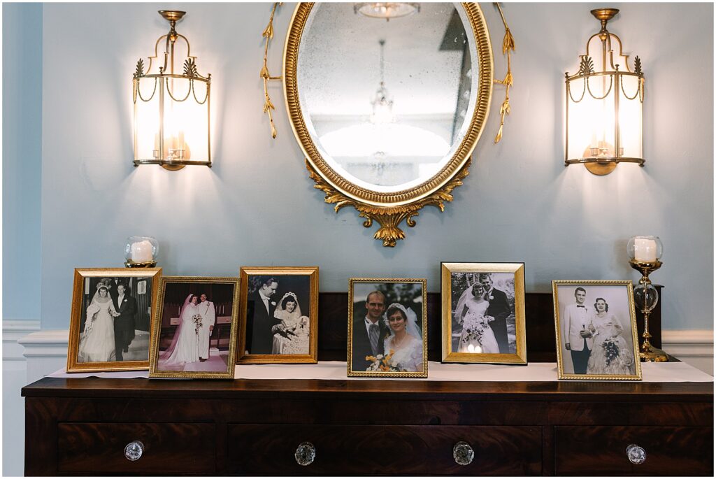 Family photos line a hall table in a historic wedding venue.
