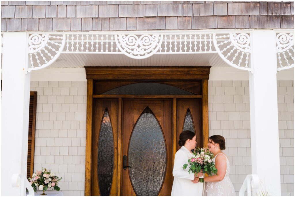 Two brides have their first look on the porch of a historic beach wedding venue.