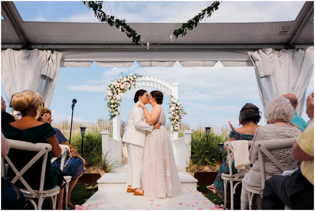 Two brides share their first kiss at their wedding at Addy Sea Historic Oceanfront Inn.