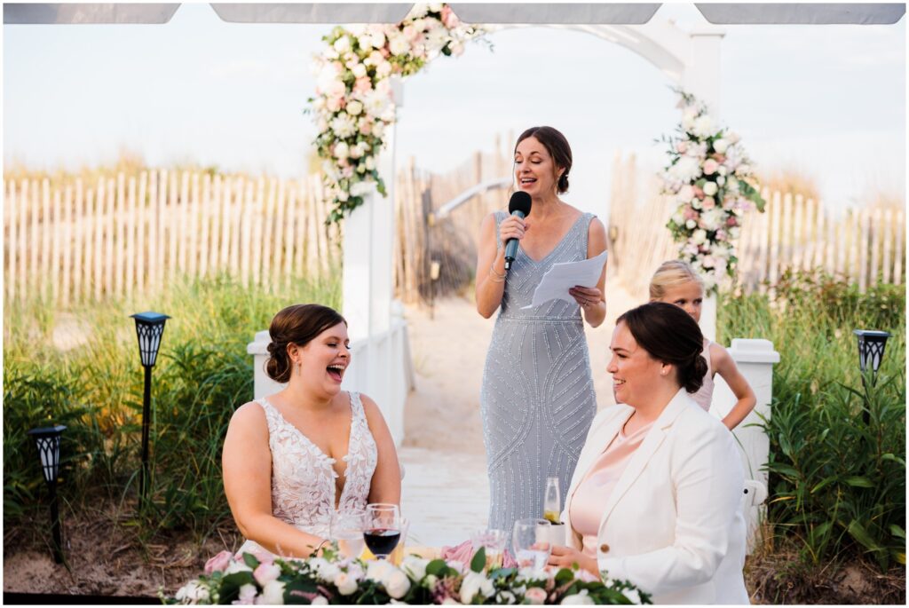 Two brides laugh during a maid of honor speech.