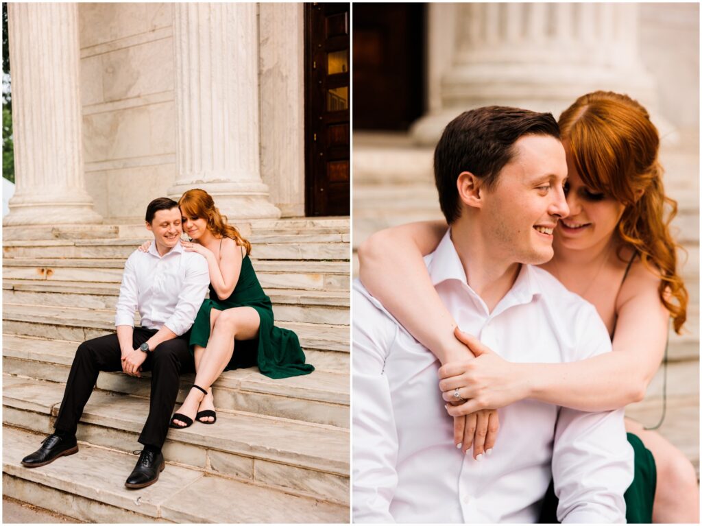 A woman sits behind her fiance on a staircase and puts her arms around his shoulders in an engagement photo.