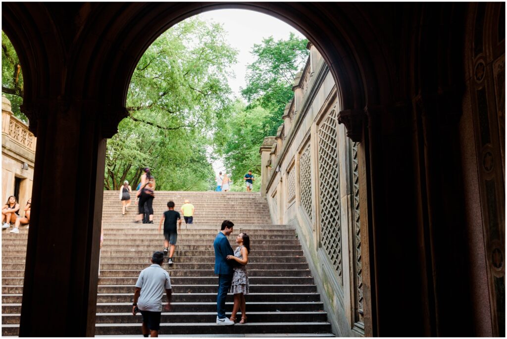 An engaged couple embraces on a staircase in Central Park.