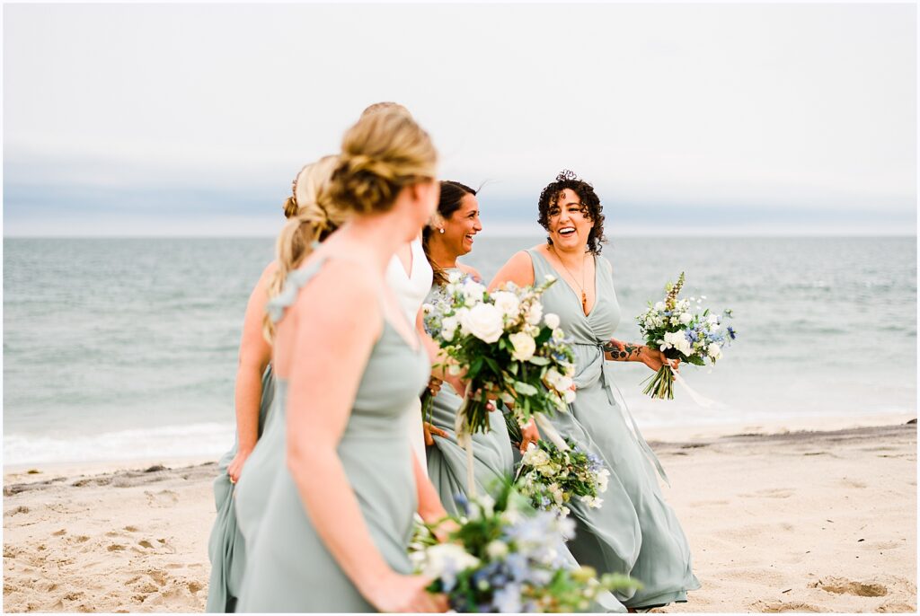 Bridesmaids laugh on the beach.