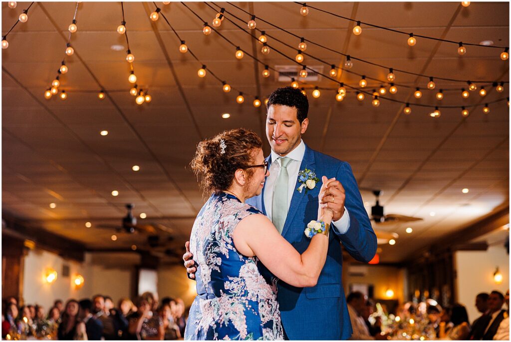 A groom smiles at his mother during the mother son dance.