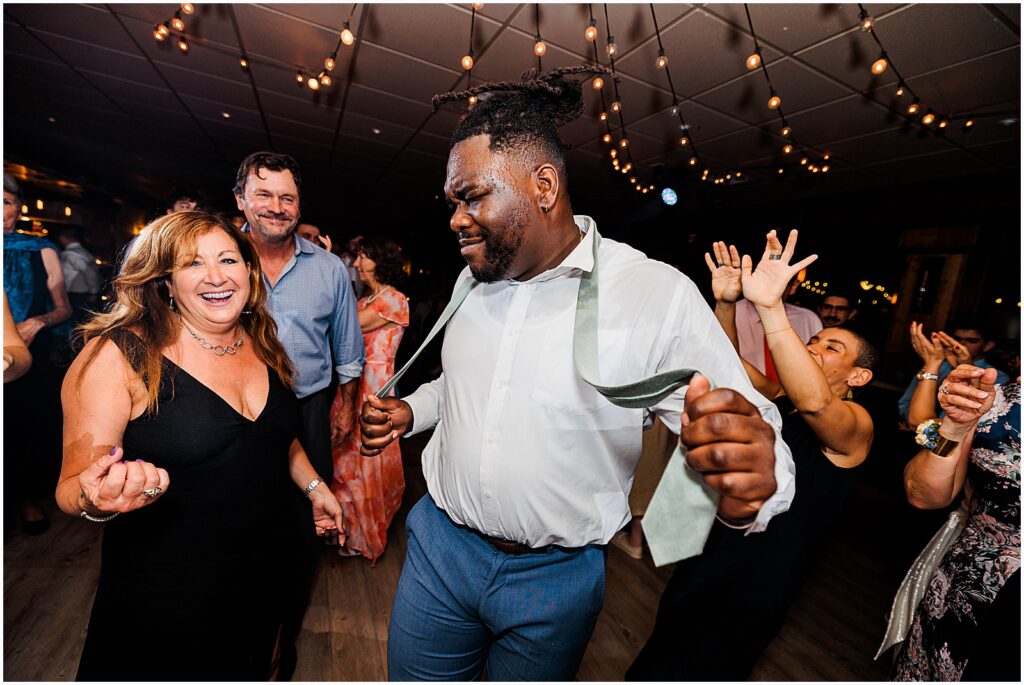A groomsman dances with a wedding guest.
