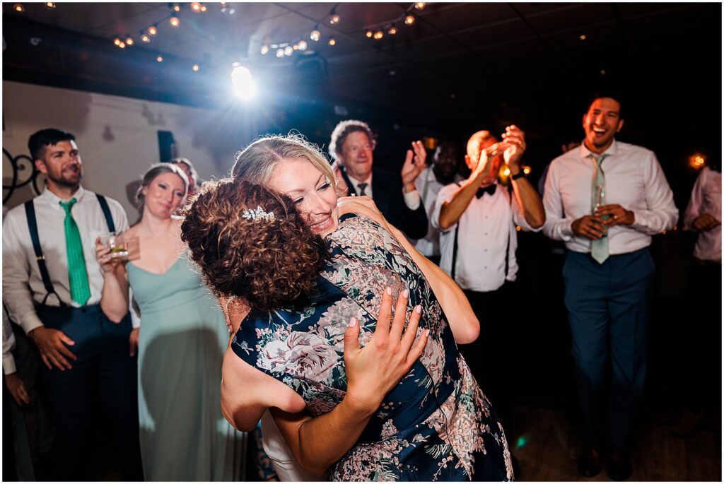 The bride hugs her mother in law on the dance floor.