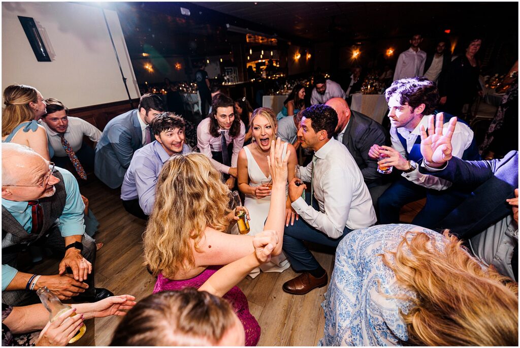 The bride and groom get low on the dance floor with guests.