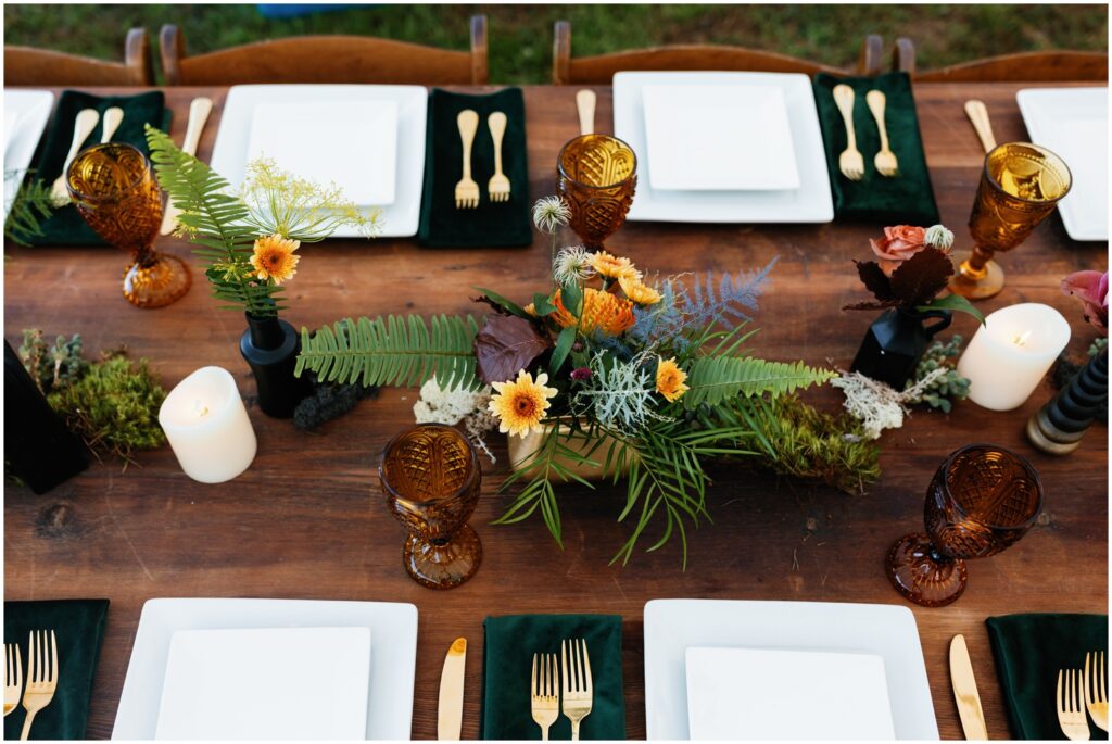 A flower arrangement sits in the middle of a reception table at a Good Earth Market wedding.