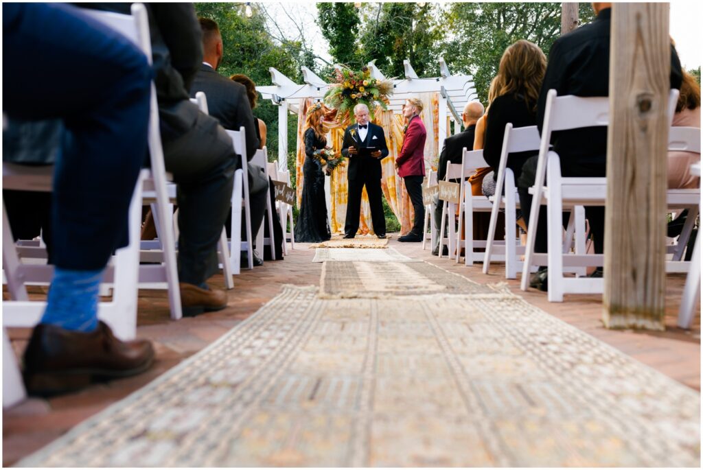 An officiant talks to a bride and groom during their fall wedding ceremony.