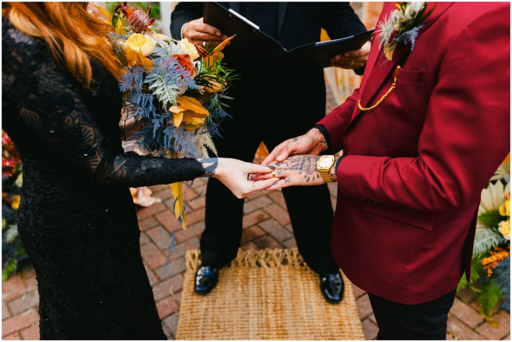 A bride places a ring on a groom's finger.