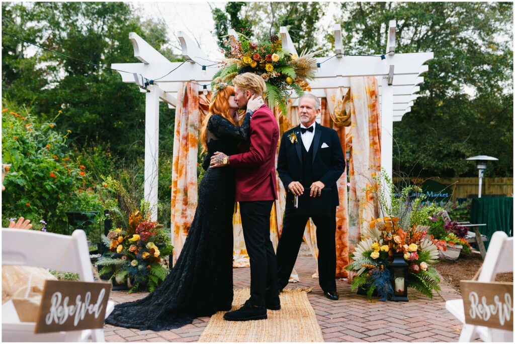 A bride and groom share their first kiss at the end of their fall wedding ceremony.