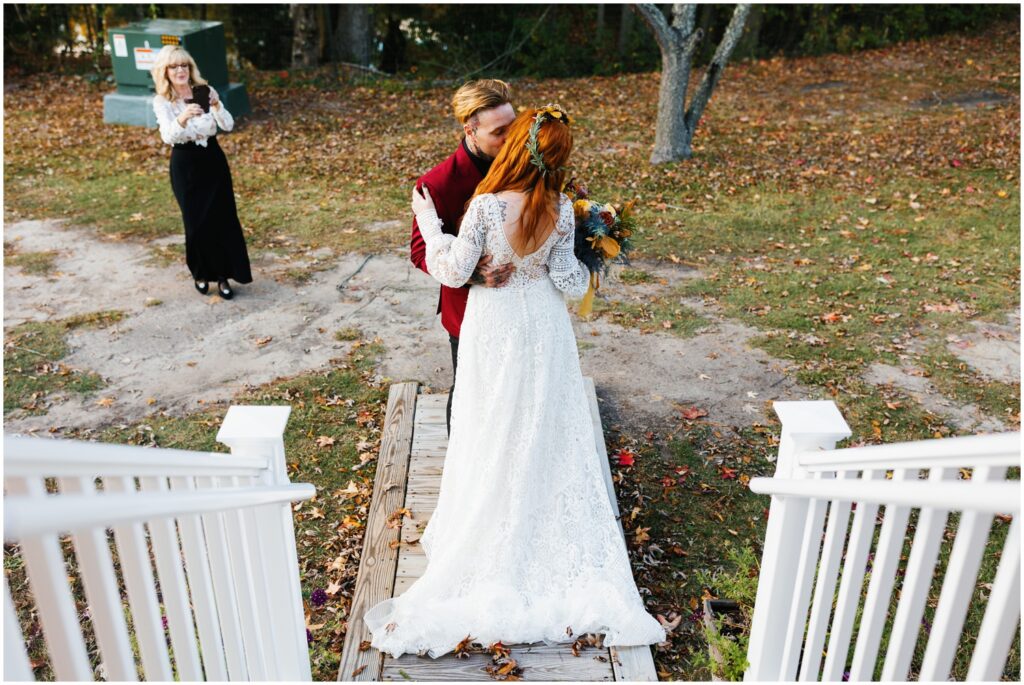A bride and groom kiss at the foot of porch stairs.