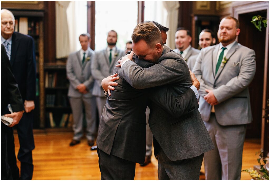 A groom embraces a family member at the altar.