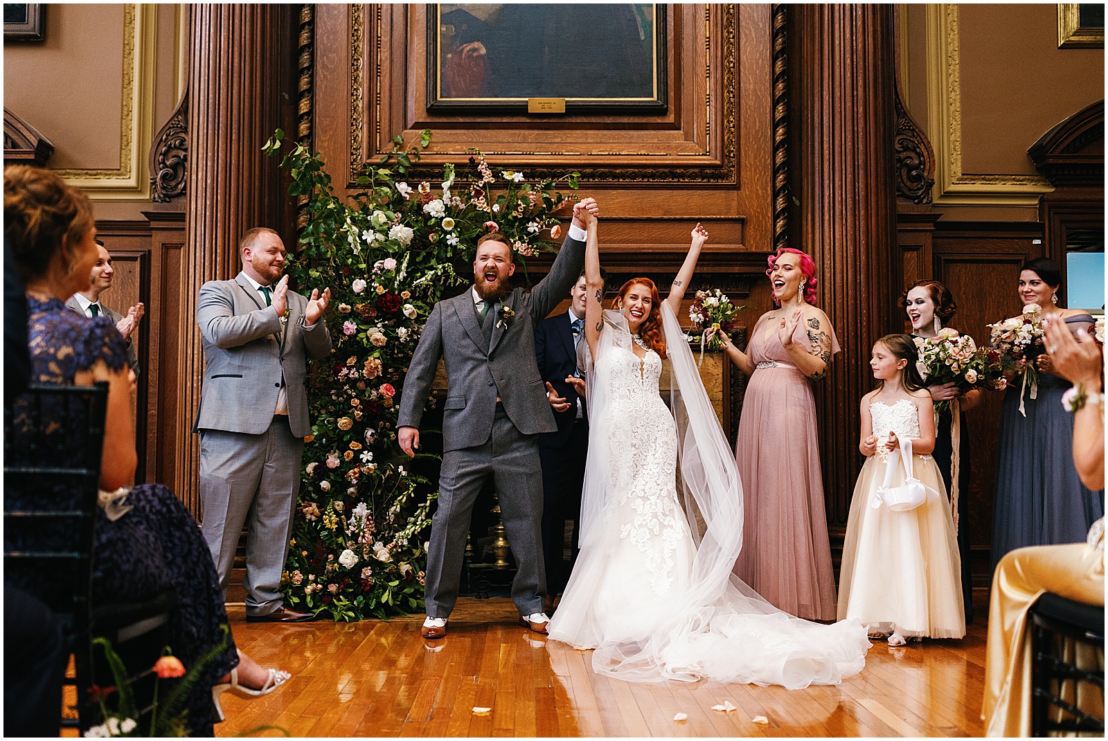 A bride and groom raise their hands in celebration after their Mutter Museum wedding ceremony.