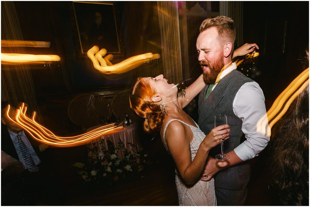A bride and groom laugh on the edge of the dance floor.