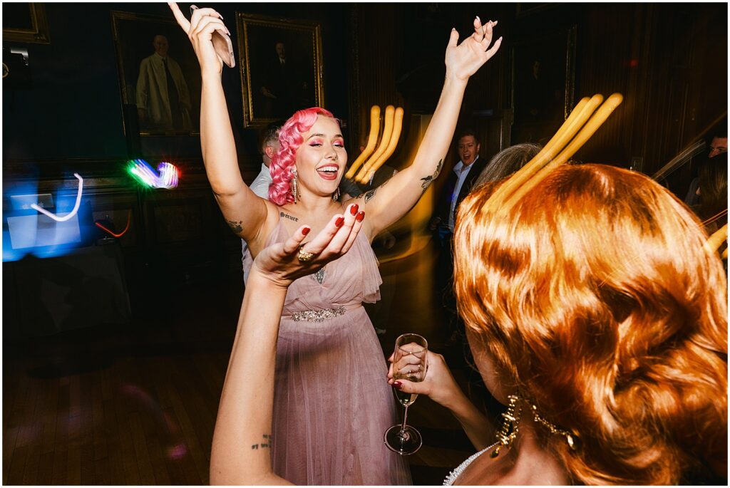 A bridesmaid raises her hands and dances.