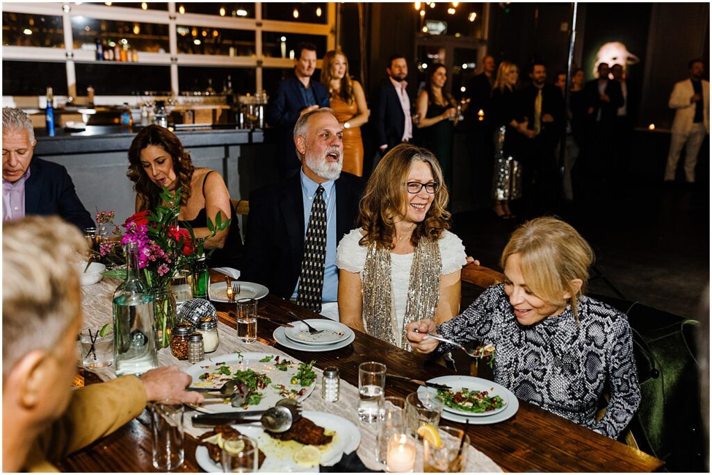 Wedding guests smile while they eat dinner at Porta.