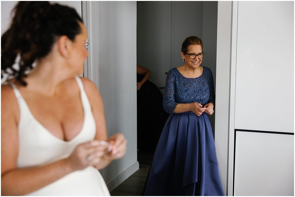 A bride turns to smile as her mom enters the room.