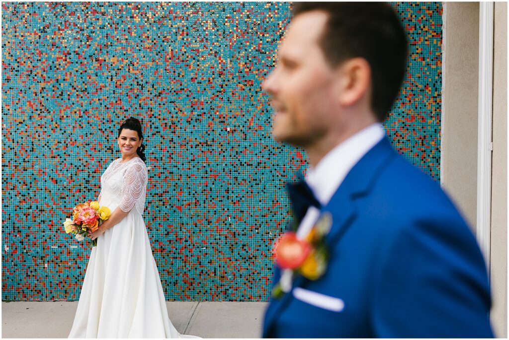 A bride and groom pose in front of a mural before their Watermark Asbury Park wedding.