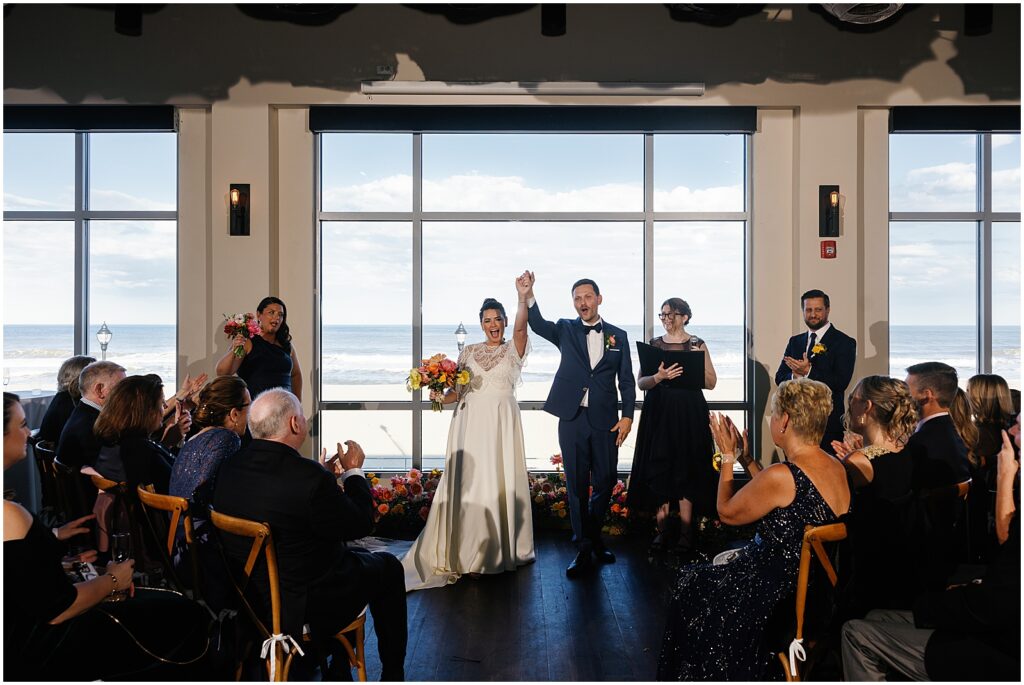 A bride and groom wave to their guests after their Watermark Asbury Park wedding ceremony.