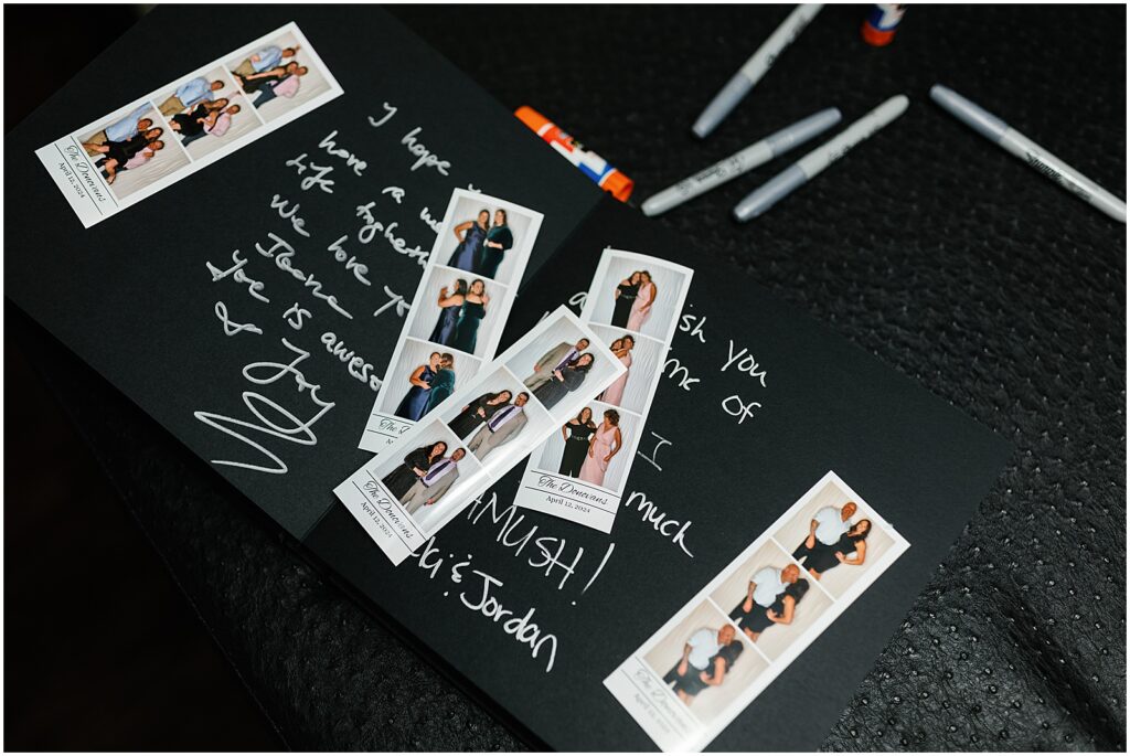 Photo booth pictures sit on a guest book with guests' messages written in white.