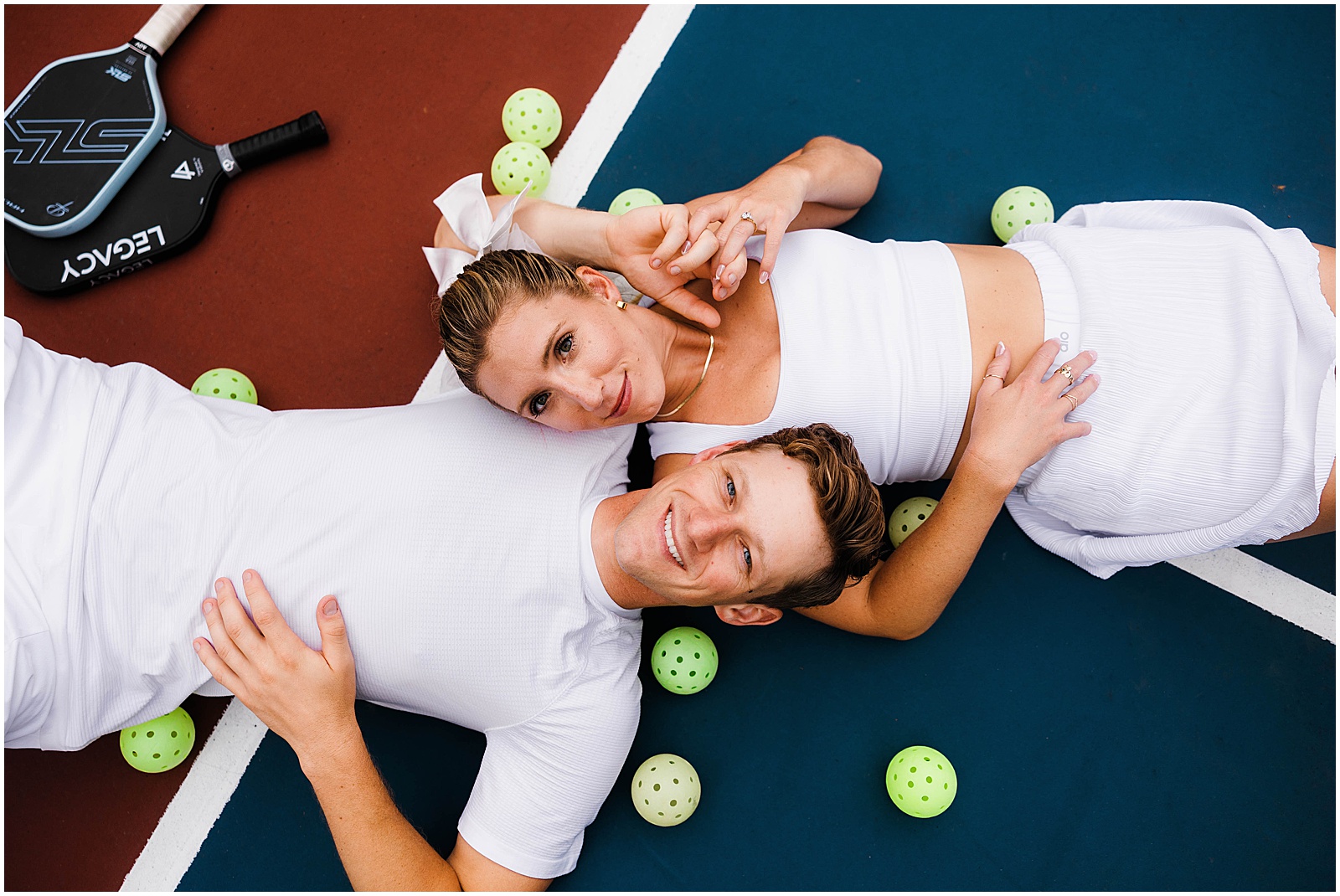 A couple lays on a pickleball court for fun engagement photos.