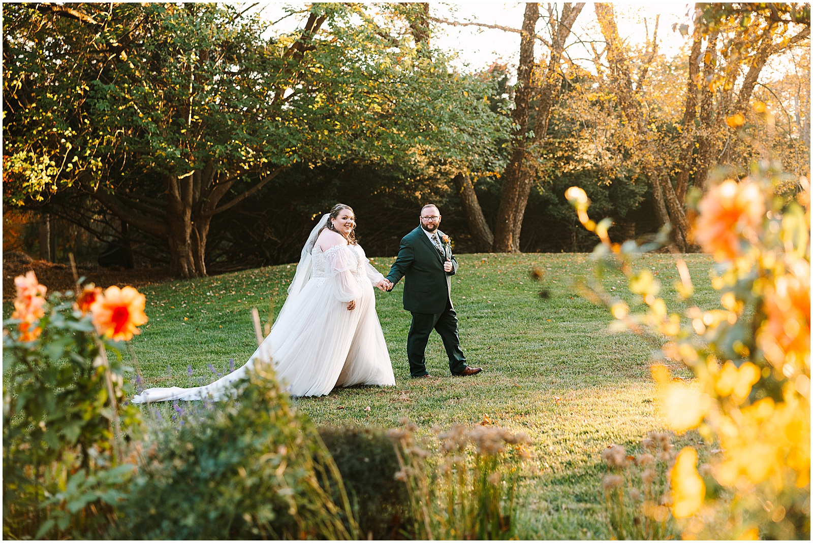 A bride and groom walk through a field at their Greenville Country Club wedding.