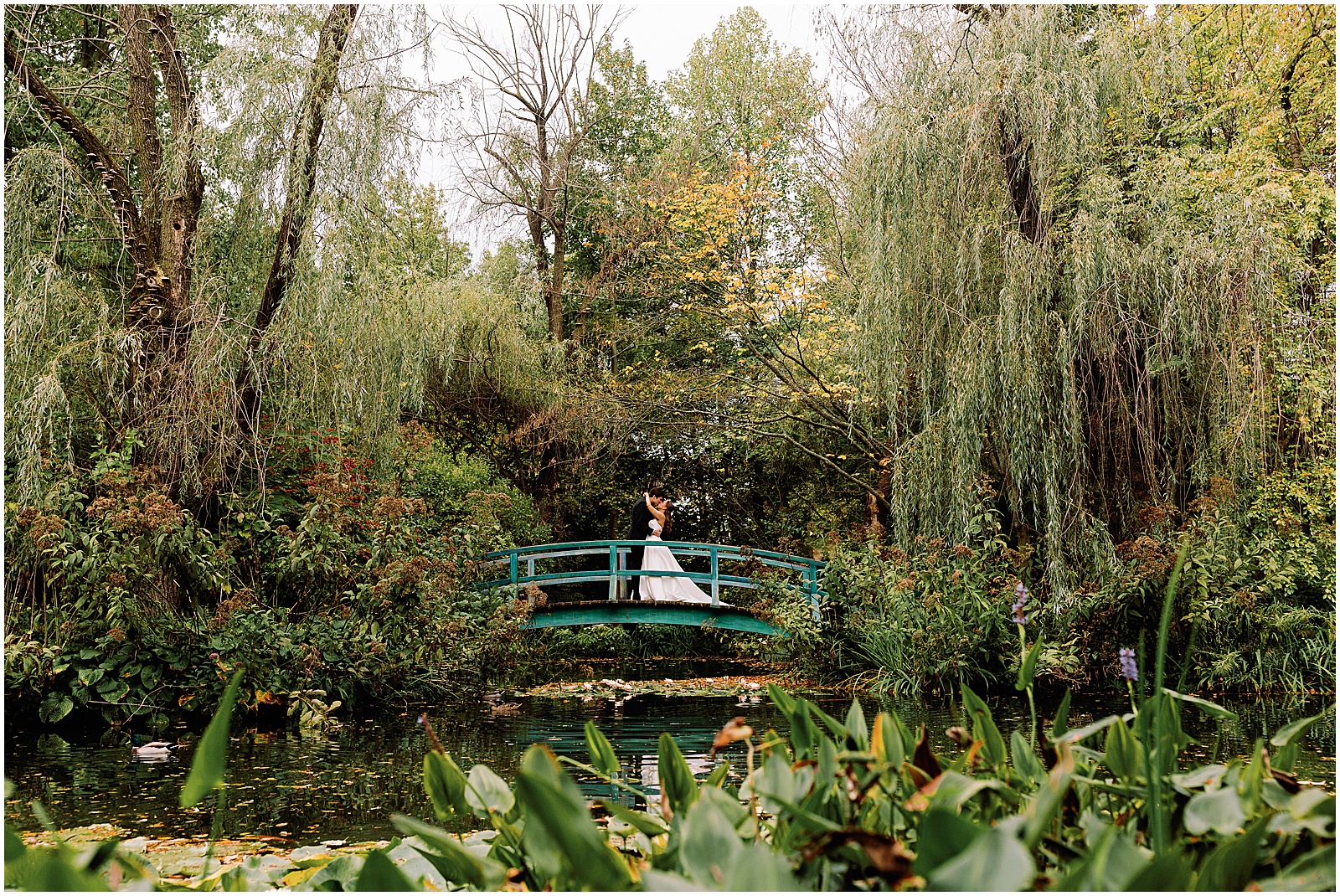 A bride and groom kiss on a blue bridge at Grounds for Sculpture.