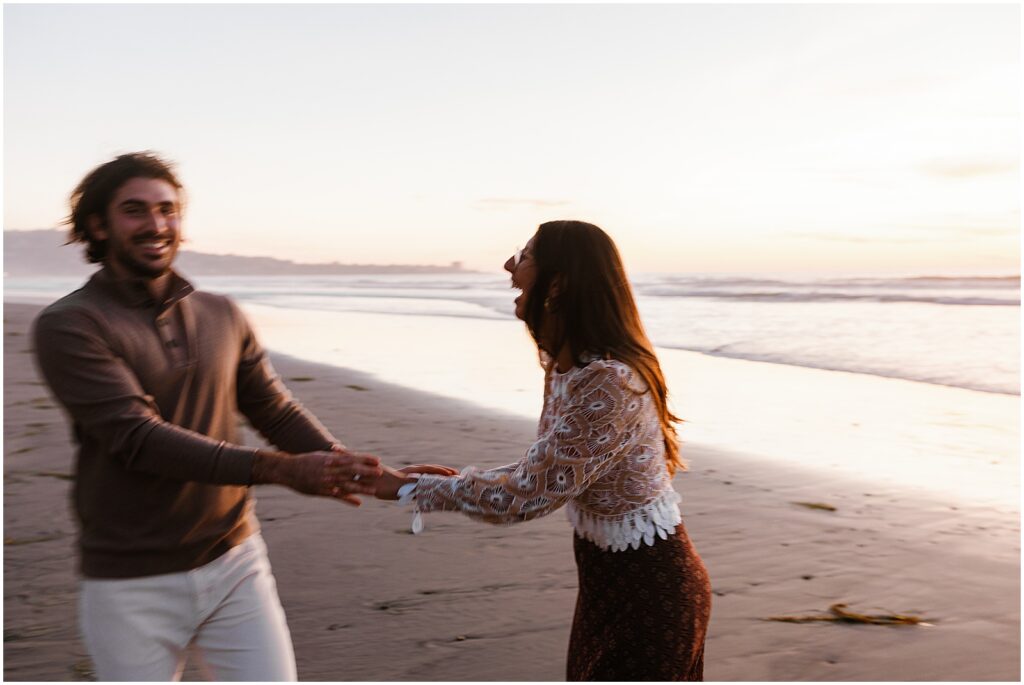 A man and woman lean towards each other laughing in San Diego engagement photos.