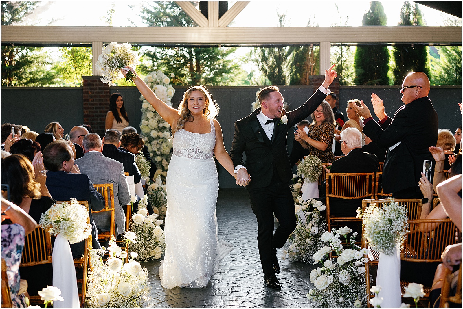 A bride and groom wave to wedding guests during a recessional at a New Jersey wedding venue.