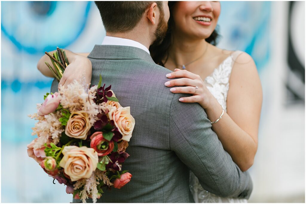 A bride and groom pose in front of a mural outside a New Jersey wedding venue.