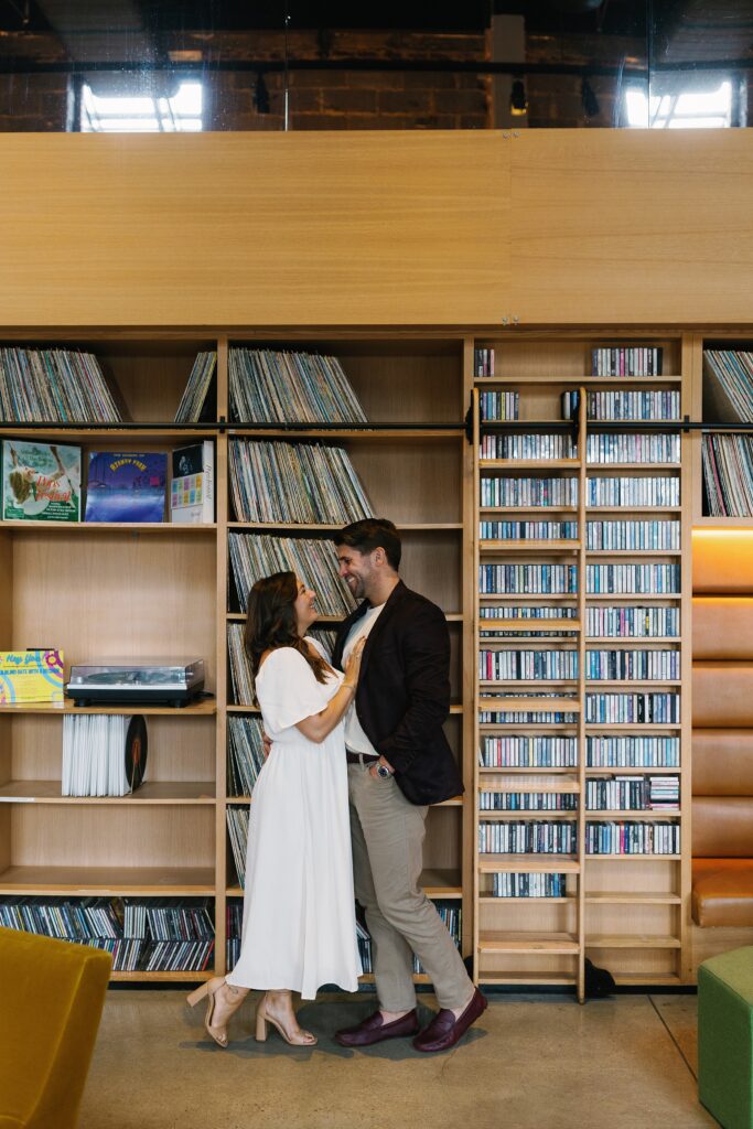 A couple stwanding in front of a record wall at the Asbury Hotel for their Asbury park engagement photos