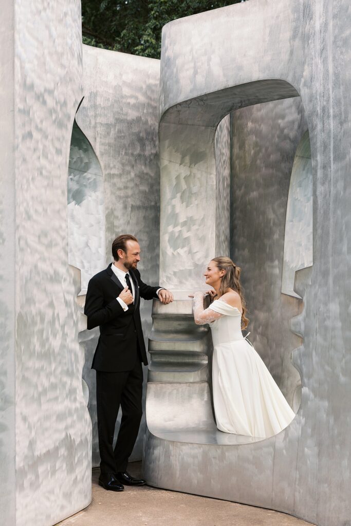 A bride and groom pose in Arch II, Set II by Elizabeth Strong-Cuevas at their Grounds for Sculpture wedding.